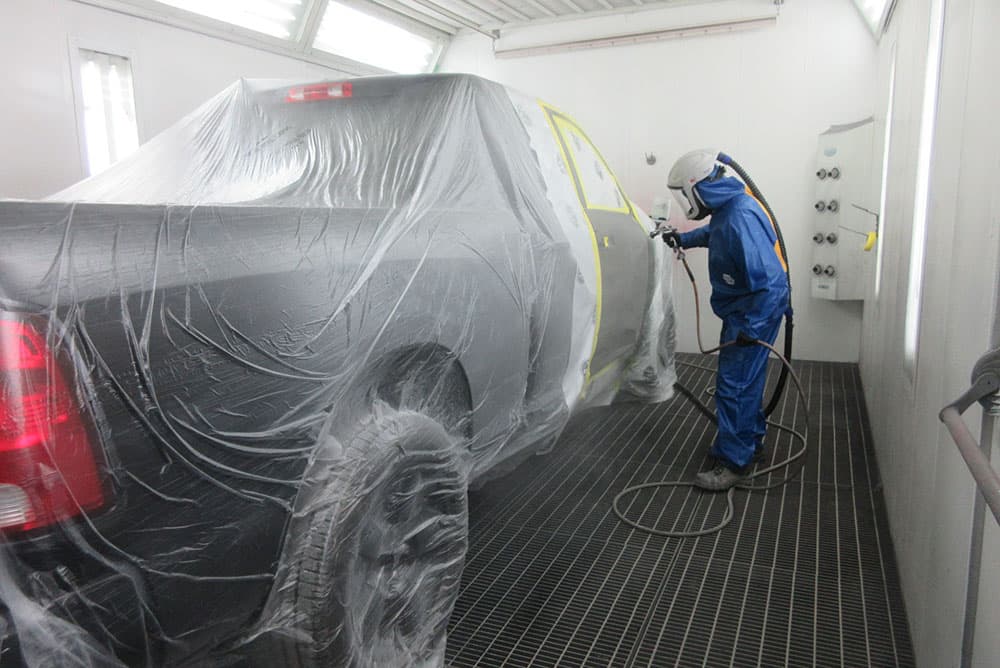 Expert spraying paint on vehicle